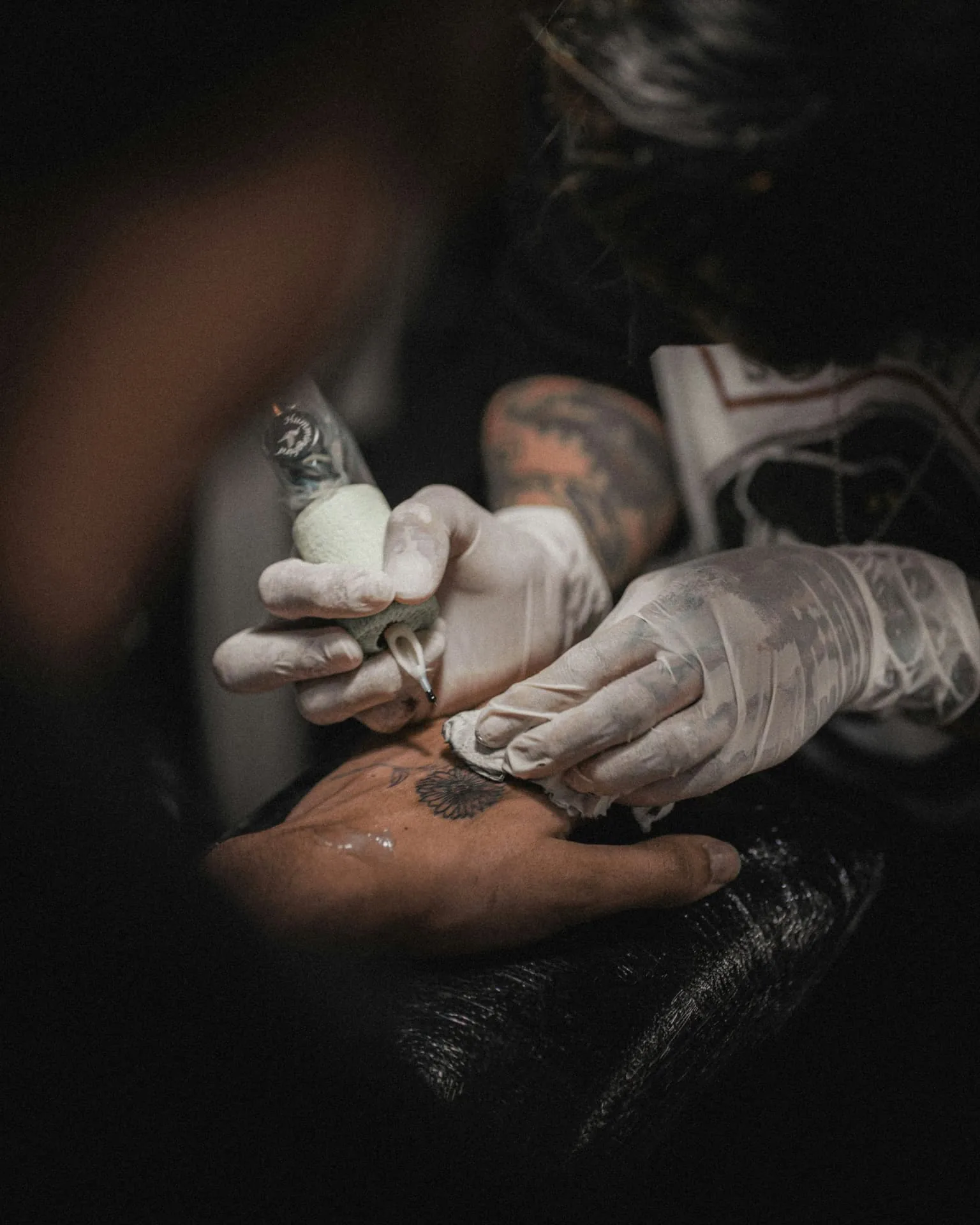 Tattoo artist working on a hand tattoo